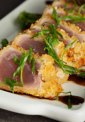 Atum empanado grelhado, fatiado e decorado com molho