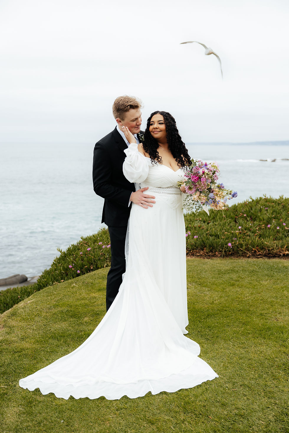 bride and groom standing near the beach