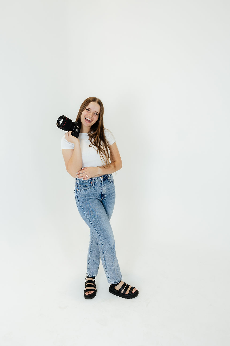 A photographer holding her camera and smiling