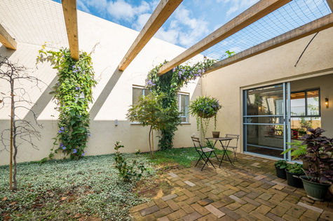 גינה יפה עם צמחים, שולחן וכיסאות, בית בעמק חפר, אווירה נעימה ומזמינה.