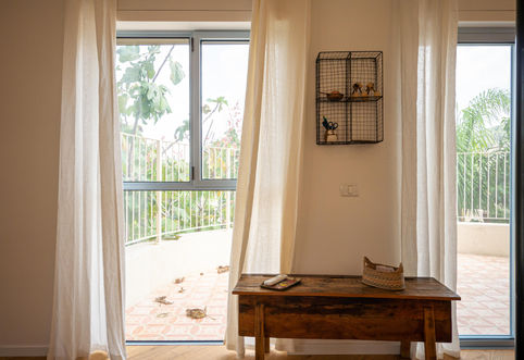 חלון עם וילונות לבנים, ספסל עץ ישן, תצוגה מעוצבת, נוף מרפסת חיצוני.