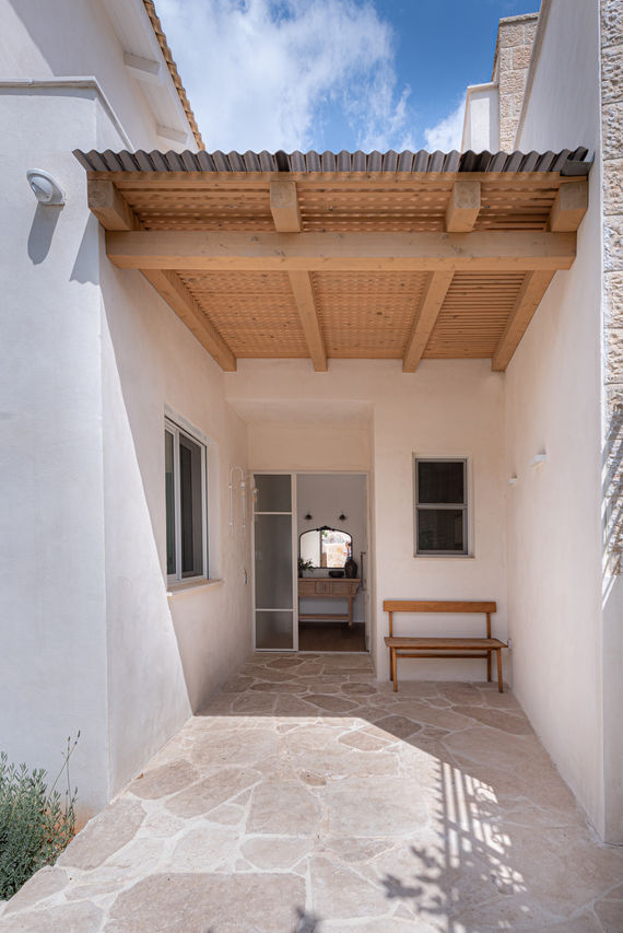 בניין לבן עם תקרה מעץ. חלון, ספסל עץ, דלת ומראה. הבית שצופה למערב AlonaSidi