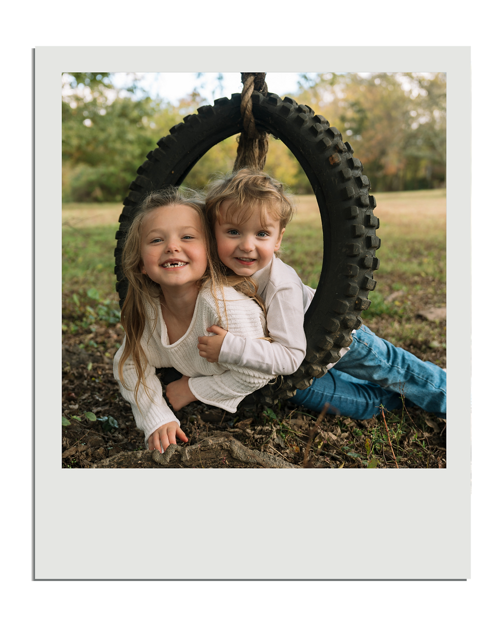 Kaleigh Madison, LLC - Two kids laying in a tire swing, family photography