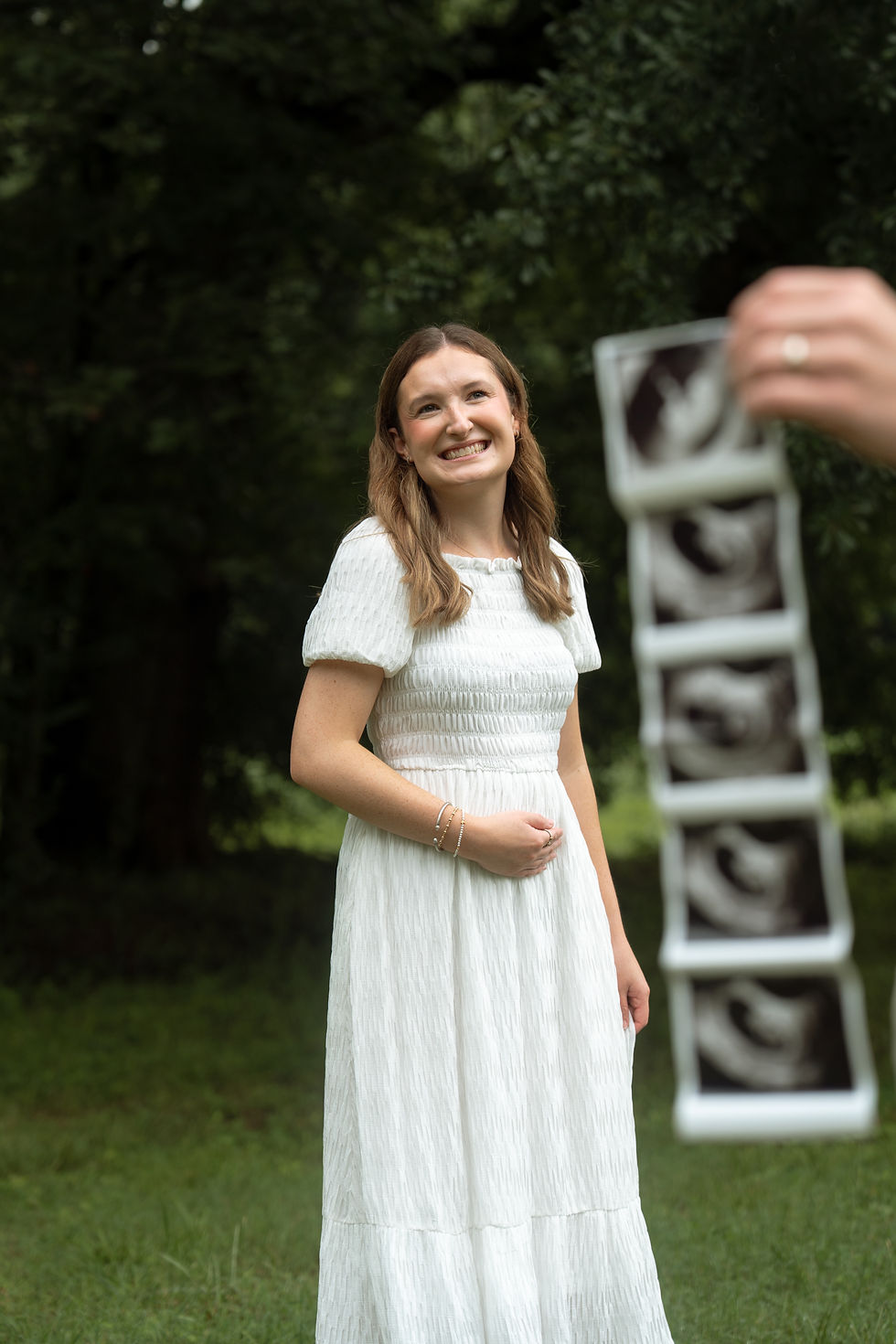 Pregnant women smiling while husband holds up ultrasound in Huntsville, AL, maternity photo by Kaleigh Madison