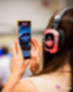 A person is holding a smartphone and recording a video of the RenderATL logo on a screen. The focus is on the phone's screen.