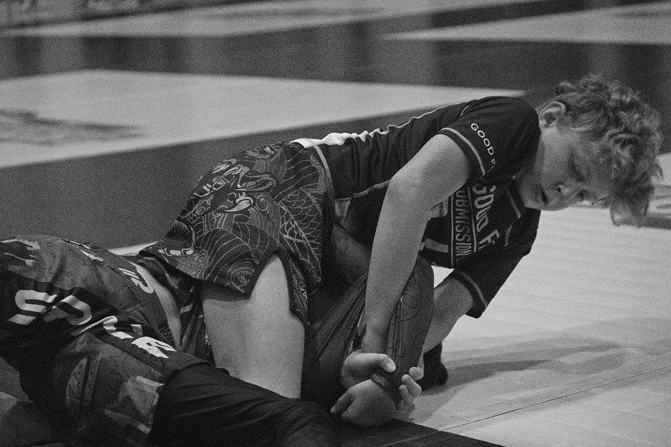 A young boy doing jiu-jitsu, using an Americana as a submission.