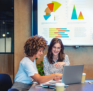 Two women sitting together looking at analytics on a laptop