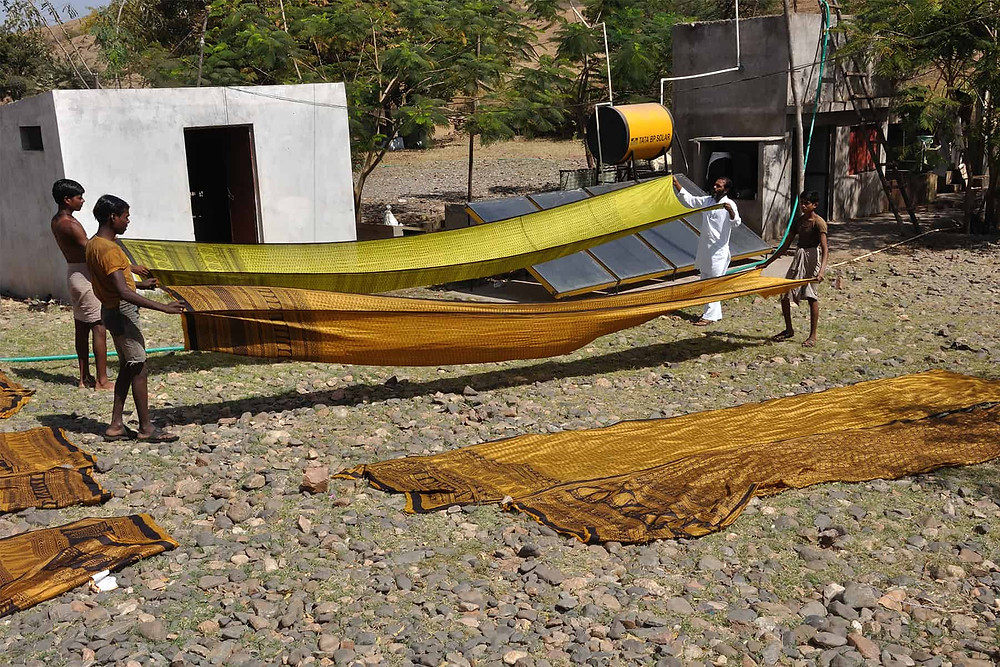 four men drying sarees for bloack printing in india