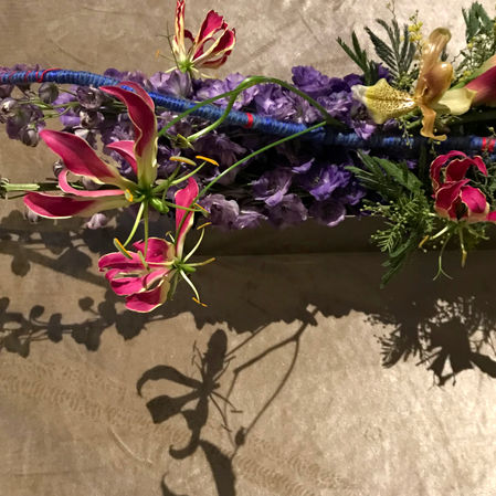 Fine art dinner table florals, delphinium, gloriosa lily, acacia mimosa, lady slipper orchid, delphinium, midolino sticks wrapped in yarn