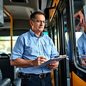 a man with a clipboard inspecting busses