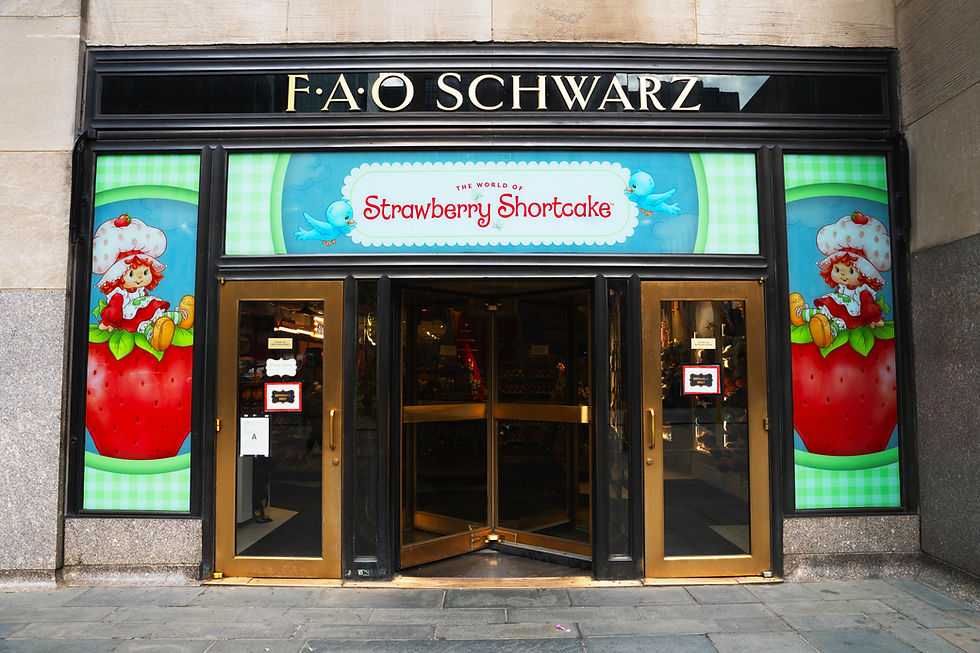 Storefront of FAO Schwartz with Strawberry Shortcake theme. Green checkered pattern, red strawberry graphics, and blue birds are visible.