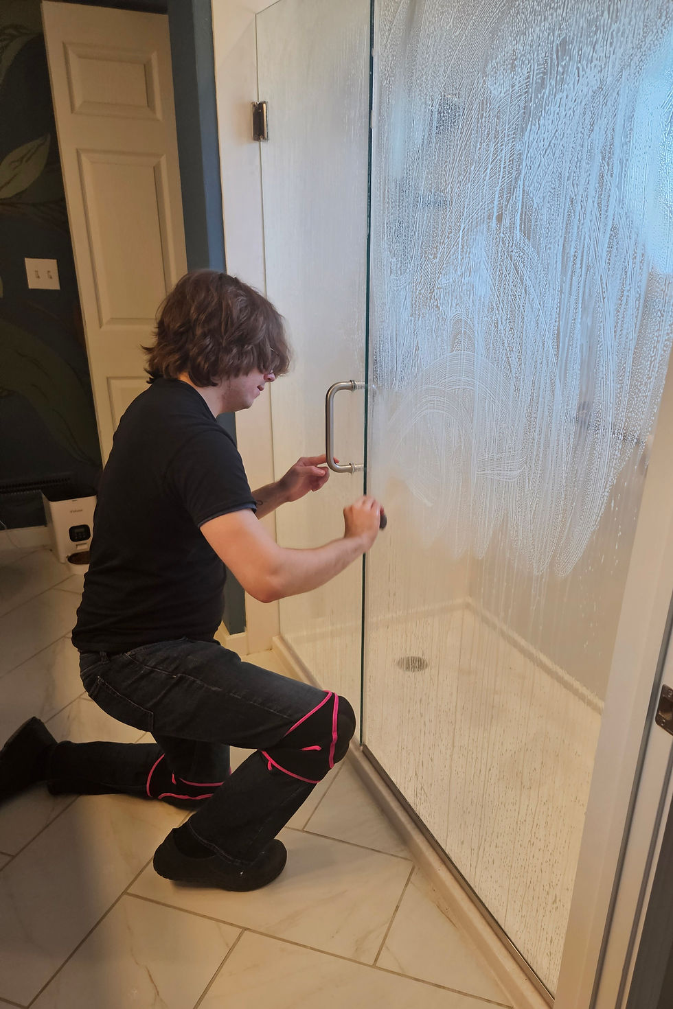 Professional cleaning service cleaning a glass shower