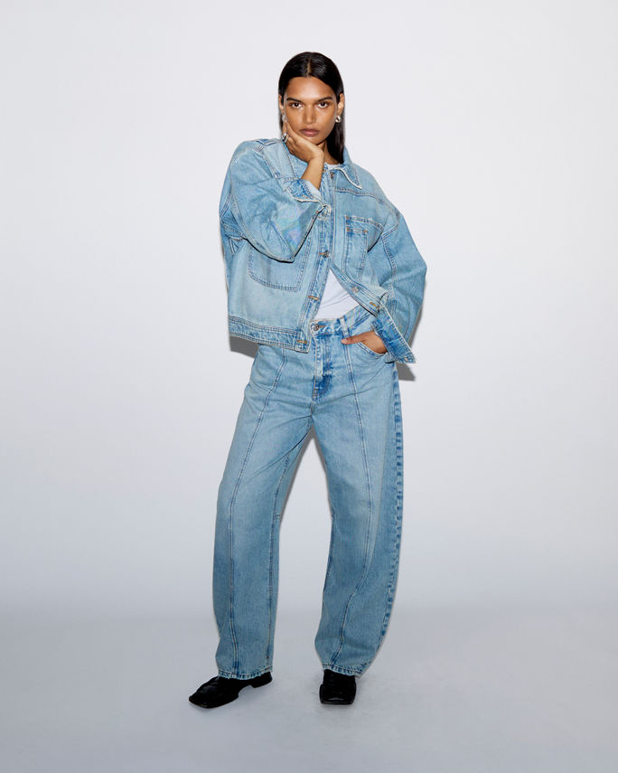 Studio lookbook capture; tailored jacket on seated model on white backdrop