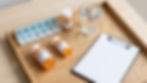 Pill organizer, medication bottles, water, and clipboard