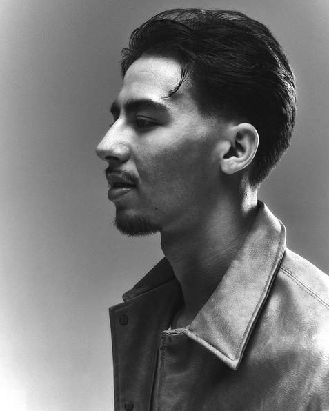 Black-and-white side profile portrait of man in collared jacket.