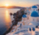 Sunset over Santorini, Greece. White buildings with blue domes overlook the sea. Warm glow illuminates the coastline, creating a serene mood.