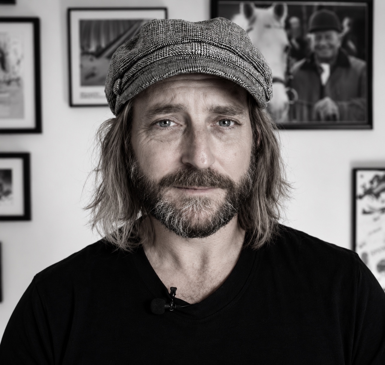 Black and white portrait of John Trager wearing his flat cap and black shirt