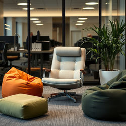 A lounge chair in an office setting surrounded by 2 bean bags