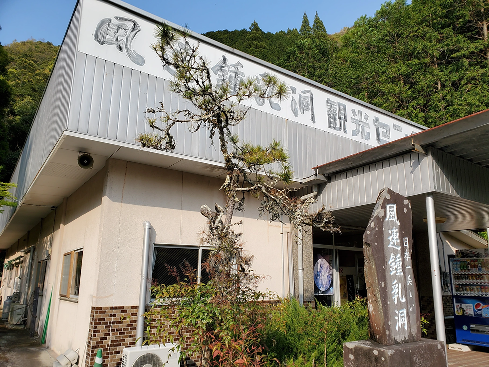 建物の外観に「風連鍾乳洞観光センター」の看板。前景に石碑と自動販売機。自然に囲まれた静かな雰囲気。