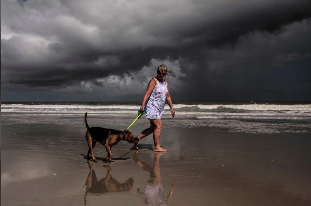 Mulher caminha com cachorro em praia de Amelia Island, em Jacksonville, antes da chegada do furacão Dorian à Flórida 01/09/2019 REUTERS/Maria Alejandra Cardona