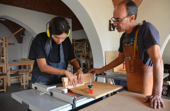 an instructor  supervising a trainee while using a table saw