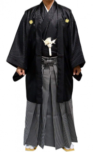A traditional Japanese men's wedding kimono, featuring a black haori jacket with a white family crest, paired with striped hakama trousers, representing classic Japanese groom attire.