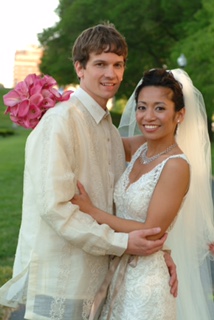 A groom wearing a Filipino Barong Tagalog, a traditional embroidered formal shirt, posing with his bride outdoors in a lush green garden, embracing cultural wedding traditions.