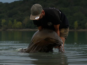 Un homme qui porte une carpe dans un sac de conservation
