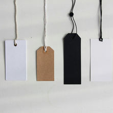 Four blank price tags in white, kraft, black, and gray hanging against a light background, representing the early-stage pricing decisions every founder must make before going to market