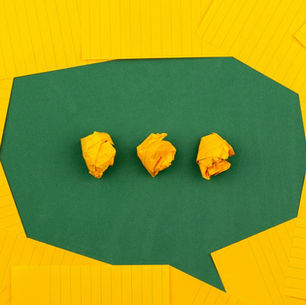 A green speech bubble made from paper containing three crumpled yellow notes, representing the questions and open dialogue at the heart of great client relationships