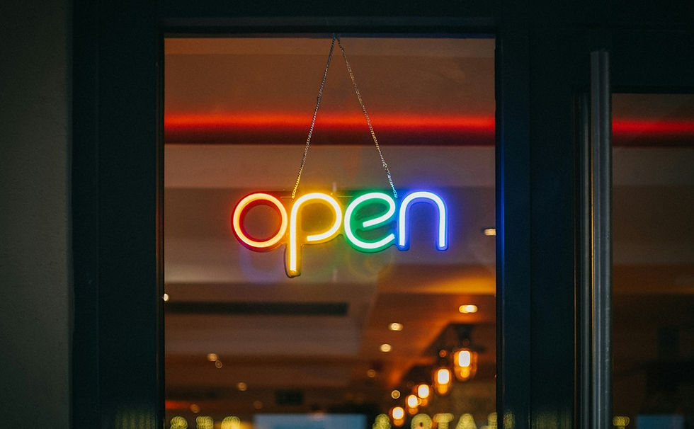 Colorful neon "open" sign hanging in a shop window in Dubai, representing the moment a founder officially opens their business for the first time.