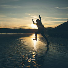 Person leaping on a beach at sunset — the moment a first-time founder moves from idea to action