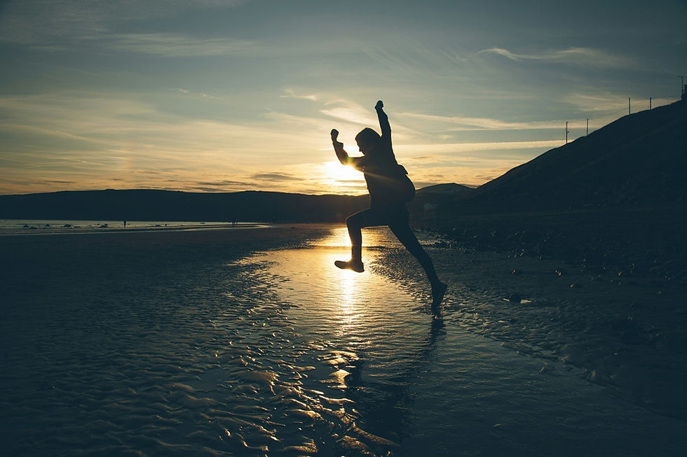 Person leaping on a beach at sunset — the moment a first-time founder moves from idea to action