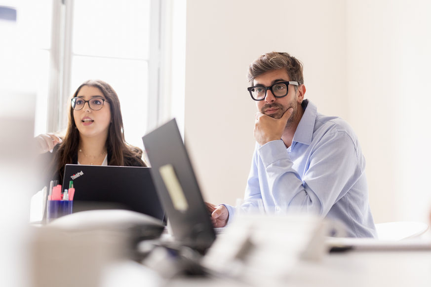 Collaborateurs concentrés lors d'un échange professionnel dans les locaux de leur entreprise.