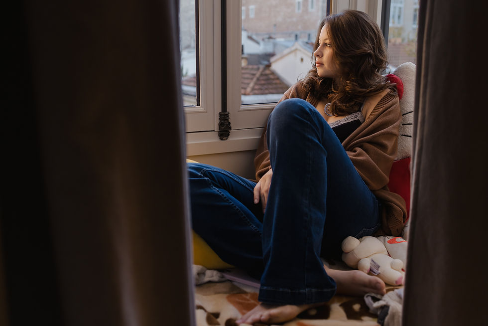 Une jeune fille parmi ses peluches qui regarde par la fenêtre