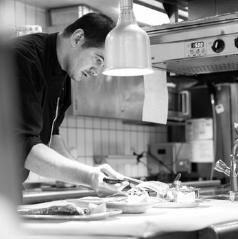 Koch bei der Zubereitung eines Gerichts in der Küche des Hotel Schweizerhof Zürich