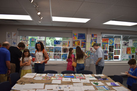 Campers and their parents appreciate all of the art during an arty party.
