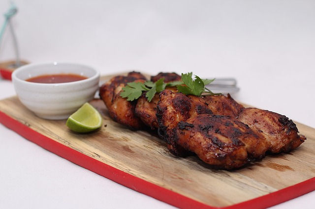 barbecue chicken with bowl of sauce, lime on a cutting board