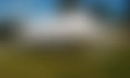 Large white pole tent set up on grass for an outdoor event.