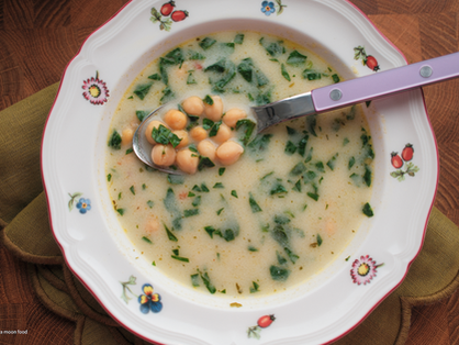 white creamy soup with chickpeas and spinach in a cosy classic soup plate