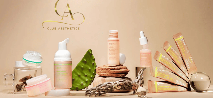 Skincare products arranged with cactus and driftwood on a beige backdrop. Logo reads "Club Aesthetics." Packaging features soft pink and green.