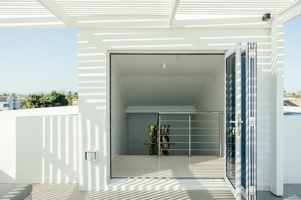 Modern rooftop entrance with white pergola and glass door