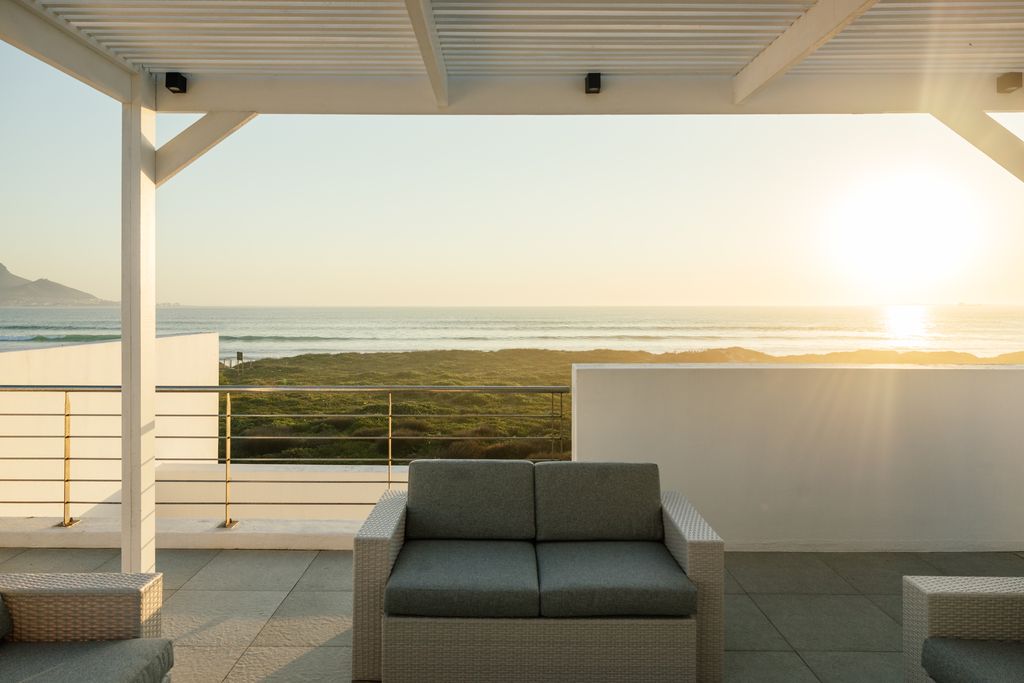 Outdoor lounge sofa on a patio overlooking the ocean at sunset