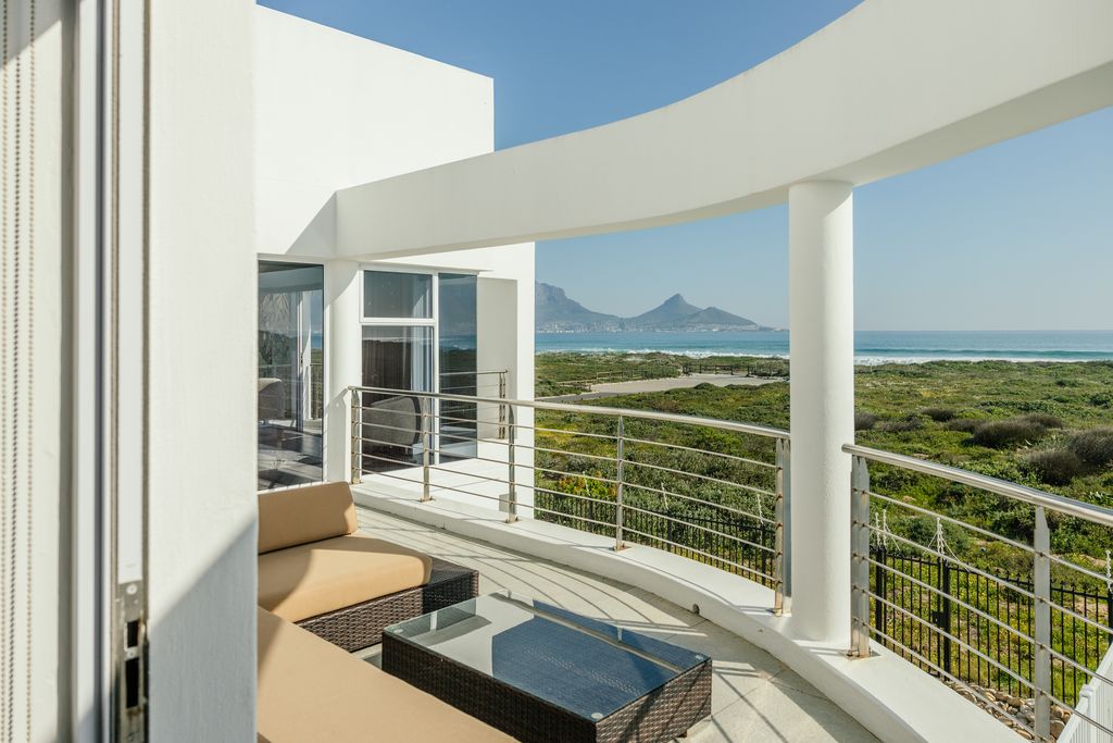 Modern white balcony with ocean and mountain views.