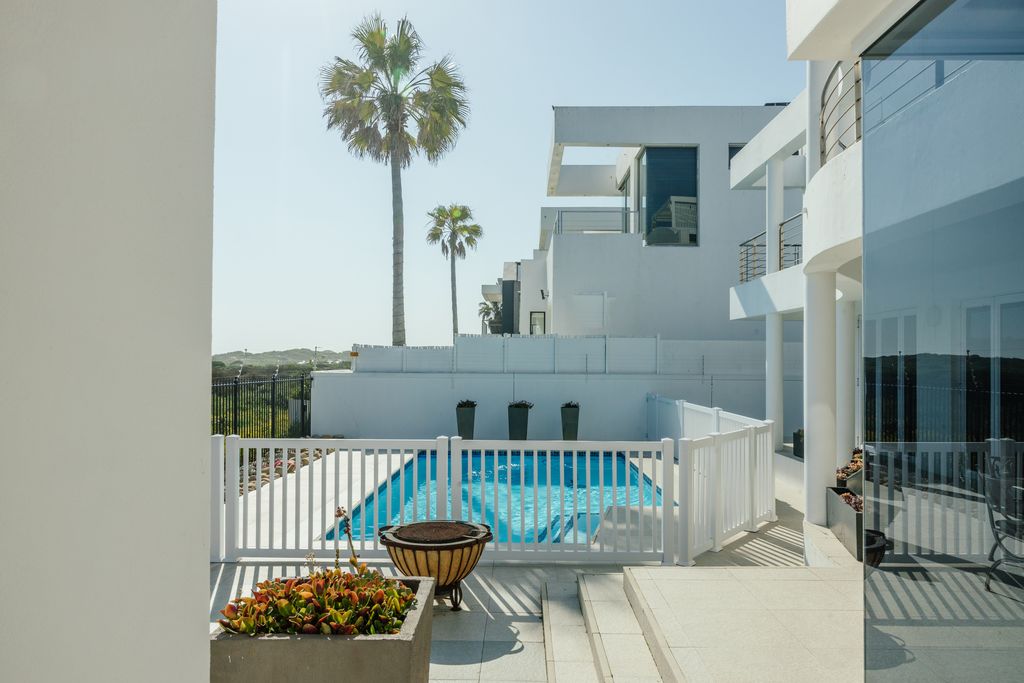 Modern white villa patio with fenced pool and palm trees