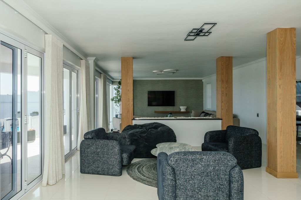 Modern open living space with grey armchairs and wooden pillars