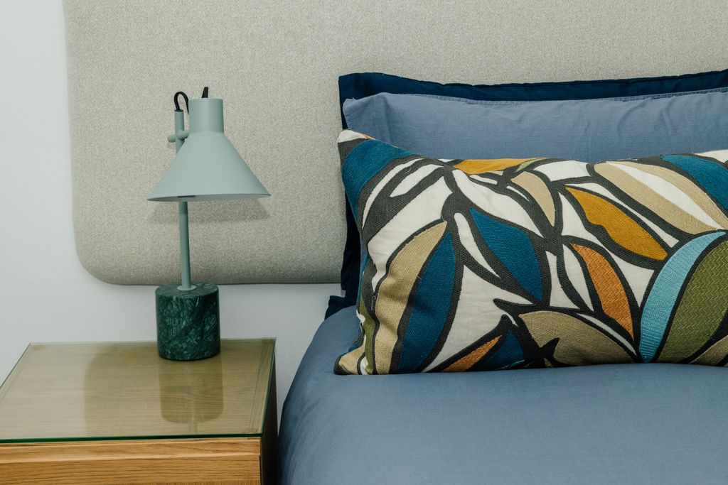 Modern bedroom with blue bedding and marble base lamp