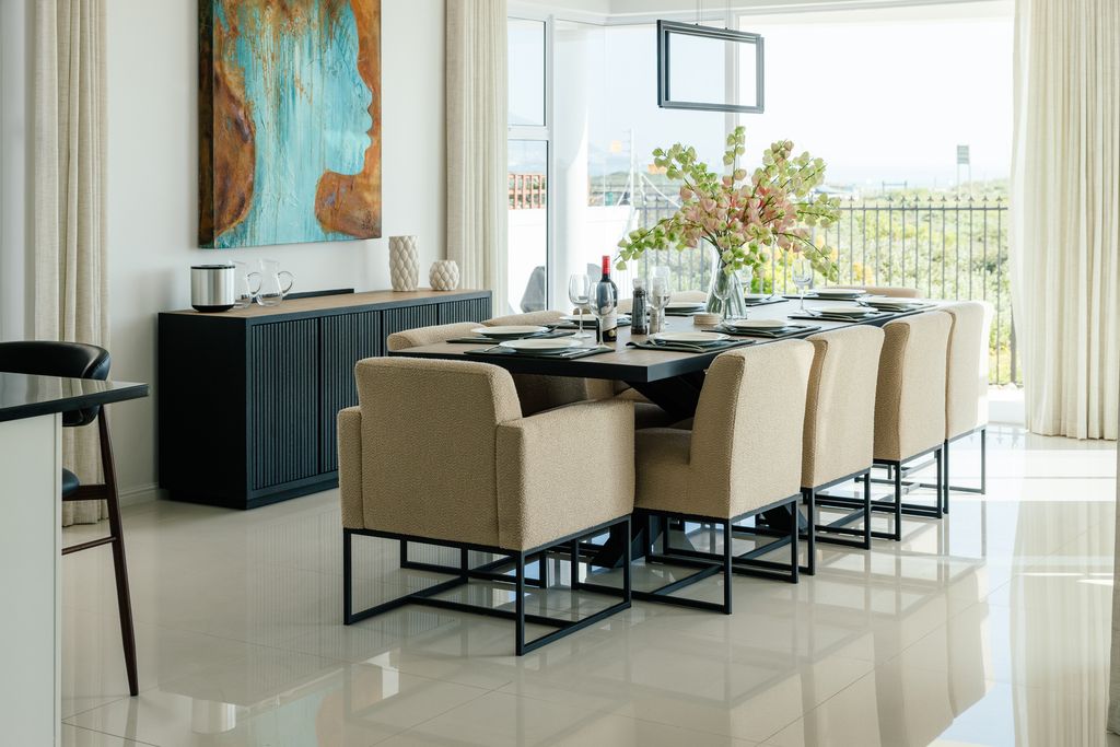 Modern dining room with a large table and beige chairs.