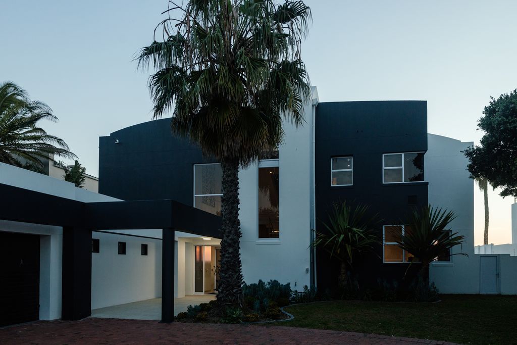 Modern two-story black and white house with palm trees