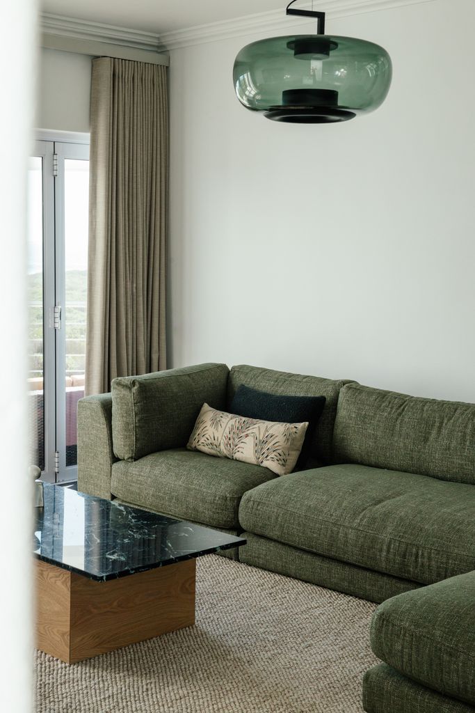Green sofa with pillows and glass pendant light